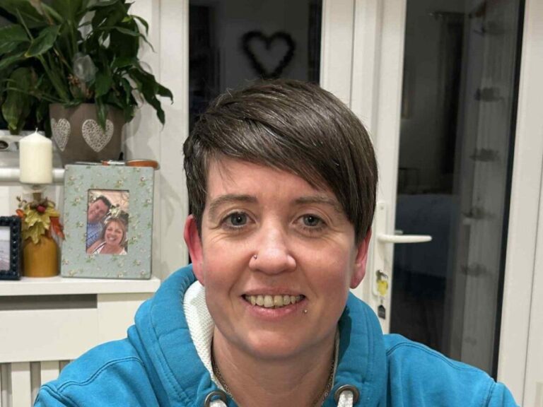 Ruth Maxwell in a bright blue hooded top, smiling at the camera